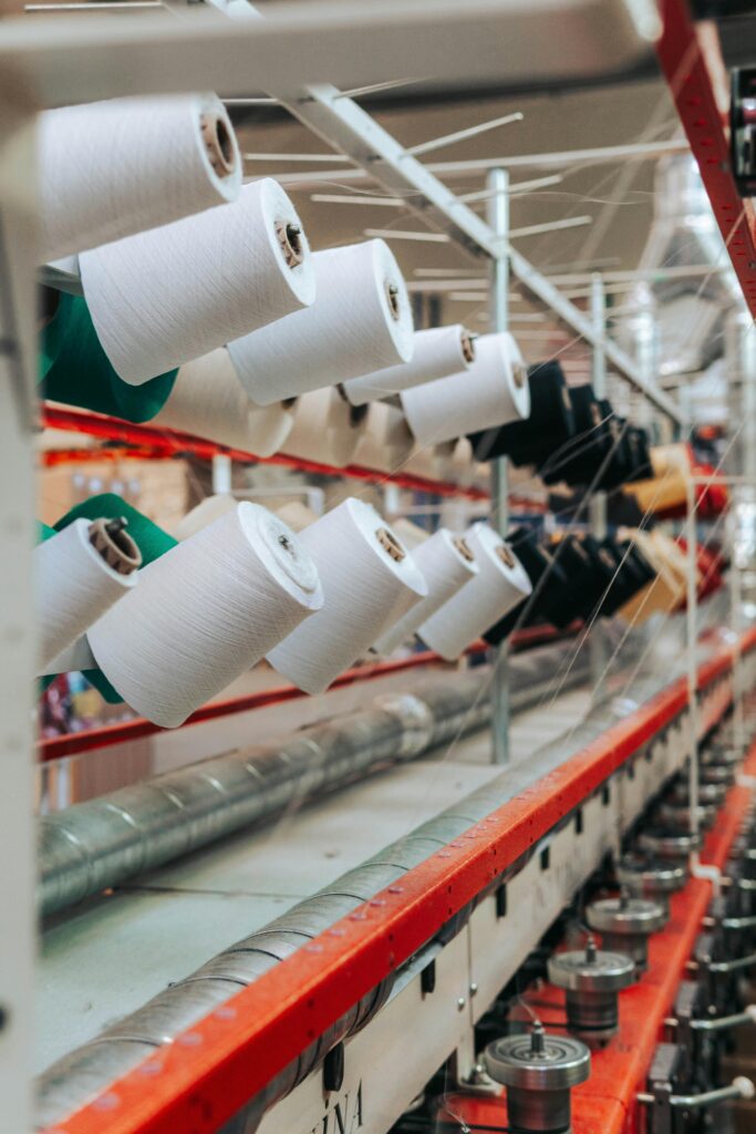 Detailed view of yarn spools in a textile factory, showcasing industrial equipment.